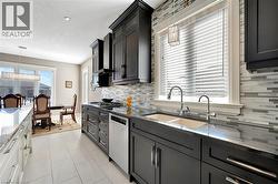 Kitchen featuring hanging light fixtures, dark stone countertops, backsplash, stainless steel appliances, and a textured ceiling - 
