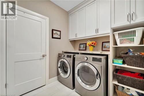 Laundry area with cabinet space, separate washer and dryer, and light tile patterned floors - 107 Forbes Crescent, Listowel, ON - Indoor Photo Showing Laundry Room