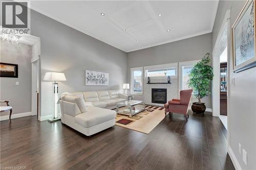 Living room featuring ornamental molding, a glass covered fireplace, dark wood-style flooring, a towering ceiling, and recessed lighting - 107 Forbes Crescent, Listowel, ON - Indoor Photo Showing Living Room With Fireplace