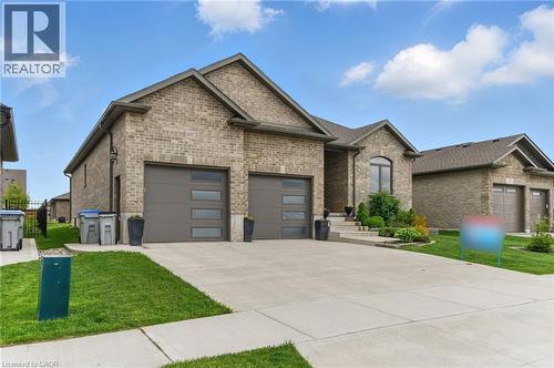 View of front of house with brick siding, an attached garage, concrete driveway, and a front lawn - 107 Forbes Crescent, Listowel, ON - Outdoor With Facade
