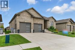 View of front of house with brick siding, an attached garage, concrete driveway, and a front lawn - 
