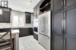 Kitchen with stainless steel appliances, open shelves, light stone countertops, light tile patterned floors, and decorative light fixtures - 