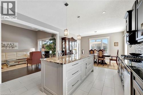 Kitchen featuring decorative light fixtures, dark stone countertops, a kitchen island, a textured ceiling, and open floor plan - 107 Forbes Crescent, Listowel, ON - Indoor Photo Showing Kitchen With Upgraded Kitchen