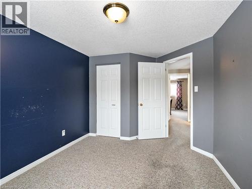 Unfurnished bedroom featuring carpet flooring, a textured ceiling, and a closet - 47 Schroder Crescent, Guelph, ON - Indoor
