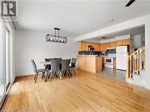 Kitchen with white appliances, hanging light fixtures, light wood-style flooring, and a peninsula - 47 Schroder Crescent, Guelph, ON - Indoor