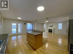 Kitchen featuring open floor plan, french doors, freestanding refrigerator, a glass covered fireplace, and light wood-style flooring - 