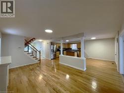 Unfurnished living room with stairs, light wood finished floors, ornate columns, and recessed lighting - 
