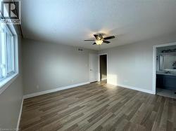 Unfurnished bedroom featuring light wood-style flooring, a textured ceiling, ceiling fan, and ensuite bathroom - 