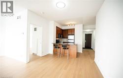 Kitchen featuring a breakfast bar, dark countertops, appliances with stainless steel finishes, a peninsula, and light wood finished floors - 