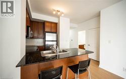 Kitchen with a peninsula, a breakfast bar, appliances with stainless steel finishes, tasteful backsplash, and dark stone counters - 