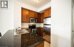 Kitchen with stainless steel appliances, tasteful backsplash, dark stone counters, a peninsula, and brown cabinetry - 