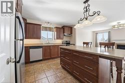 Kitchen with a breakfast bar area, decorative light fixtures, a center island, and stainless steel appliances - 