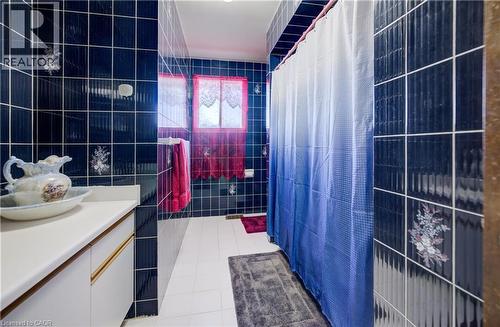 Full bathroom featuring tile walls, light tile patterned floors, vanity, and a shower with curtain - 42 Ruffian Road, Brantford, ON - Indoor Photo Showing Bathroom