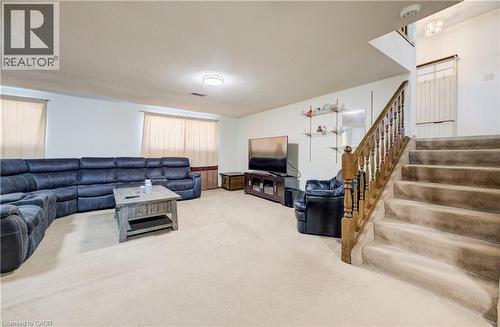 Carpeted recreation room with a textured ceiling and stairs - 42 Ruffian Road, Brantford, ON - Indoor
