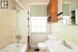 Full bathroom featuring  shower combination, vanity, decorative backsplash, and tile walls - 