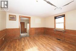 Spare room with hardwood / wood-style flooring, wood walls, and wainscoting - 