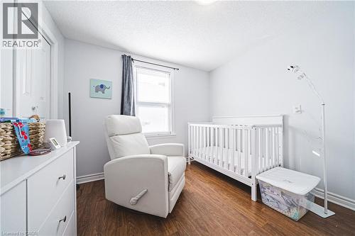 Bedroom with dark wood-style floors, a crib, and a textured ceiling - 143 Fairfield Avenue, Hamilton, ON - Indoor Photo Showing Bedroom