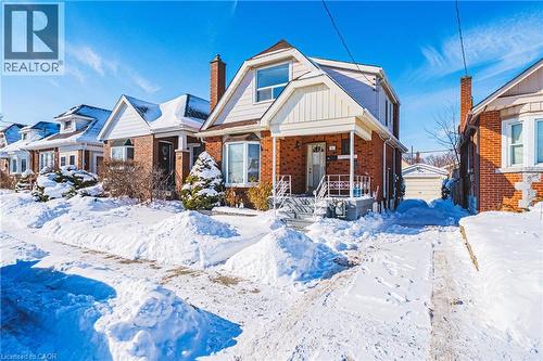Bungalow-style house featuring brick siding, a porch, an outbuilding, board and batten siding, and a chimney - 143 Fairfield Avenue, Hamilton, ON - Outdoor With Facade