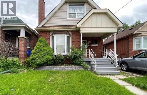 Bungalow-style house featuring brick siding, a front lawn, a porch, a chimney, and board and batten siding - 143 Fairfield Avenue, Hamilton, ON - Outdoor