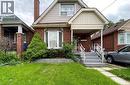 Bungalow-style house featuring brick siding, a front lawn, a porch, a chimney, and board and batten siding - 143 Fairfield Avenue, Hamilton, ON  - Outdoor 