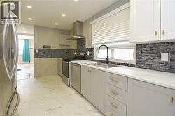 Kitchen featuring stainless steel appliances, exhaust hood, recessed lighting, and light stone countertops - 