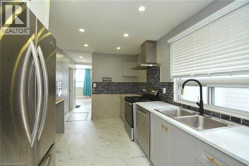 Kitchen featuring stainless steel appliances, wall chimney exhaust hood, recessed lighting, decorative backsplash, and light marble finish floors - 371 Fairfield Avenue, Hamilton, ON - Indoor Photo Showing Kitchen With Double Sink With Upgraded Kitchen