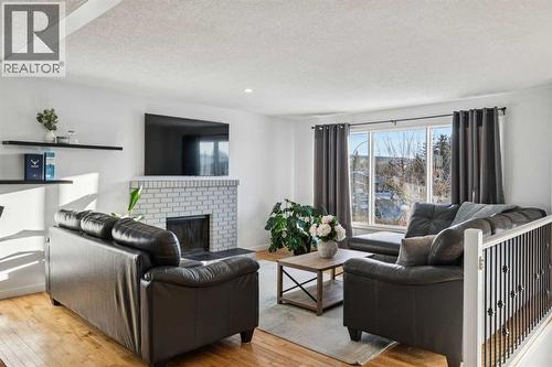 Spacious living room with wood burning fireplace - 14 Glenhill Crescent, Cochrane, AB - Indoor Photo Showing Living Room With Fireplace