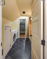 Washroom with dark tile patterned floors, lofted ceiling, and washing machine and dryer - 