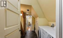 Laundry area with arched walkways, independent washer and dryer, dark tile patterned floors, and vaulted ceiling - 