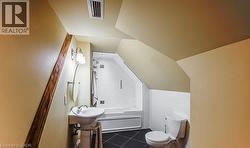 Full bathroom with shower / bath combination, dark tile patterned flooring, vaulted ceiling, and tile walls - 