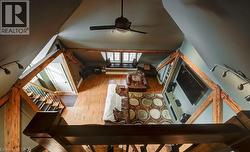 Living area featuring light wood-style floors, lofted ceiling, stairway, and a ceiling fan - 