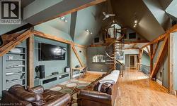 Living area featuring wood-type flooring, vaulted ceiling, stairs, and rail lighting - 