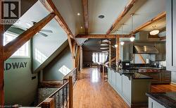 Kitchen with pendant lighting, light wood-type flooring, wall chimney exhaust hood, a kitchen bar, and beam ceiling - 