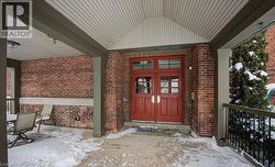 Snow covered property entrance featuring brick siding and a porch - 