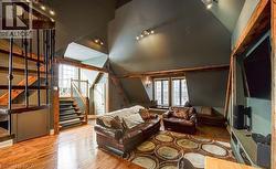 Living area featuring stairway, wood finished floors, and vaulted ceiling - 