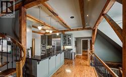 Kitchen featuring pendant lighting, a kitchen bar, light wood-type flooring, glass insert cabinets, and stainless steel appliances - 