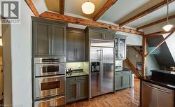 Kitchen featuring appliances with stainless steel finishes, pendant lighting, glass insert cabinets, a warming drawer, and light wood-type flooring - 