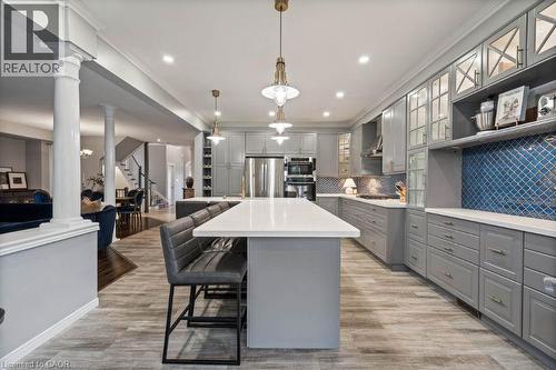 Kitchen with glass insert cabinets, gray cabinets, a kitchen breakfast bar, a center island, and tasteful backsplash - 151 Fair Street, Ancaster, ON 