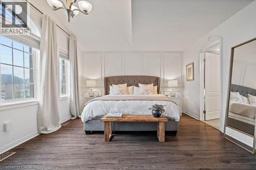 Bedroom with dark wood-style floors, a decorative wall, and a chandelier - 151 Fair Street, Ancaster, ON 