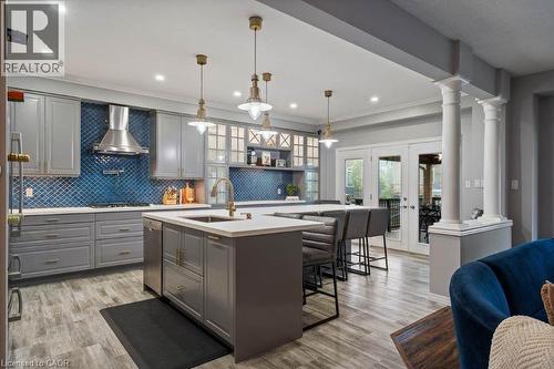 Kitchen featuring french doors, gray cabinetry, light wood-style flooring, ornamental molding, and ornate columns - 151 Fair Street, Ancaster, ON 