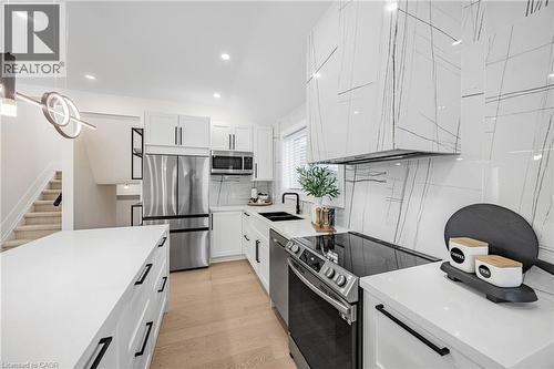 Kitchen featuring appliances with stainless steel finishes, light stone counters, white cabinetry, tasteful backsplash, and vaulted ceiling - 248 Wales Crescent, Oakville, ON - Indoor Photo Showing Kitchen With Double Sink With Upgraded Kitchen