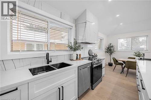 Kitchen with white cabinetry, appliances with stainless steel finishes, light wood finished floors, light stone countertops, and recessed lighting - 248 Wales Crescent, Oakville, ON - Indoor Photo Showing Kitchen With Double Sink