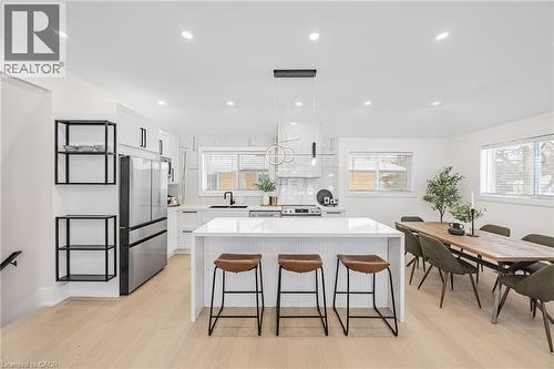 Kitchen featuring a center island, white cabinets, a breakfast bar area, pendant lighting, and appliances with stainless steel finishes - 248 Wales Crescent, Oakville, ON - Indoor