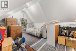 Bedroom with vaulted ceiling, wood finished floors, and rail lighting - 