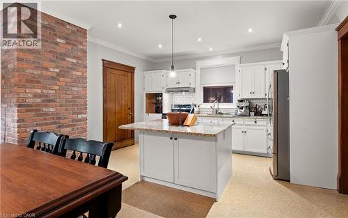 Kitchen with white cabinets, light stone countertops, hanging light fixtures, tasteful backsplash, and ornamental molding - 58 Hohner Avenue, Kitchener, ON - Indoor