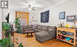 Living room with light wood-style flooring, crown molding, and a ceiling fan - 