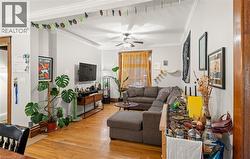 Living area with light wood finished floors, ornamental molding, and ceiling fan - 