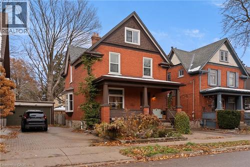 View of front facade featuring an outbuilding, brick siding, covered porch, and a chimney - 58 Hohner Avenue, Kitchener, ON - Outdoor With Deck Patio Veranda With Facade