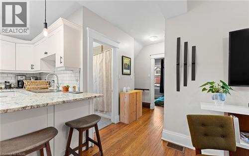 Kitchen featuring light stone countertops, light wood finished floors, backsplash, white cabinetry, and hanging light fixtures - 58 Hohner Avenue, Kitchener, ON - Indoor Photo Showing Kitchen
