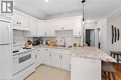 Kitchen featuring white appliances, a peninsula, tasteful backsplash, and pendant lighting - 58 Hohner Avenue, Kitchener, ON - Indoor Photo Showing Kitchen
